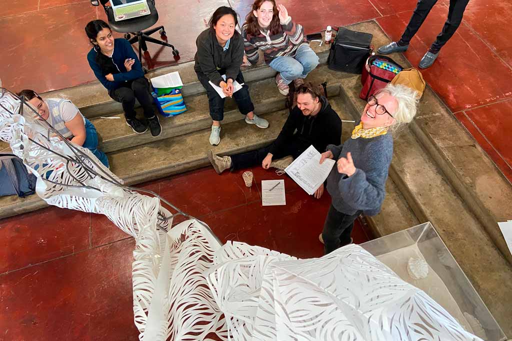 A group sculpture project made of paper, surrounded by students at UT
