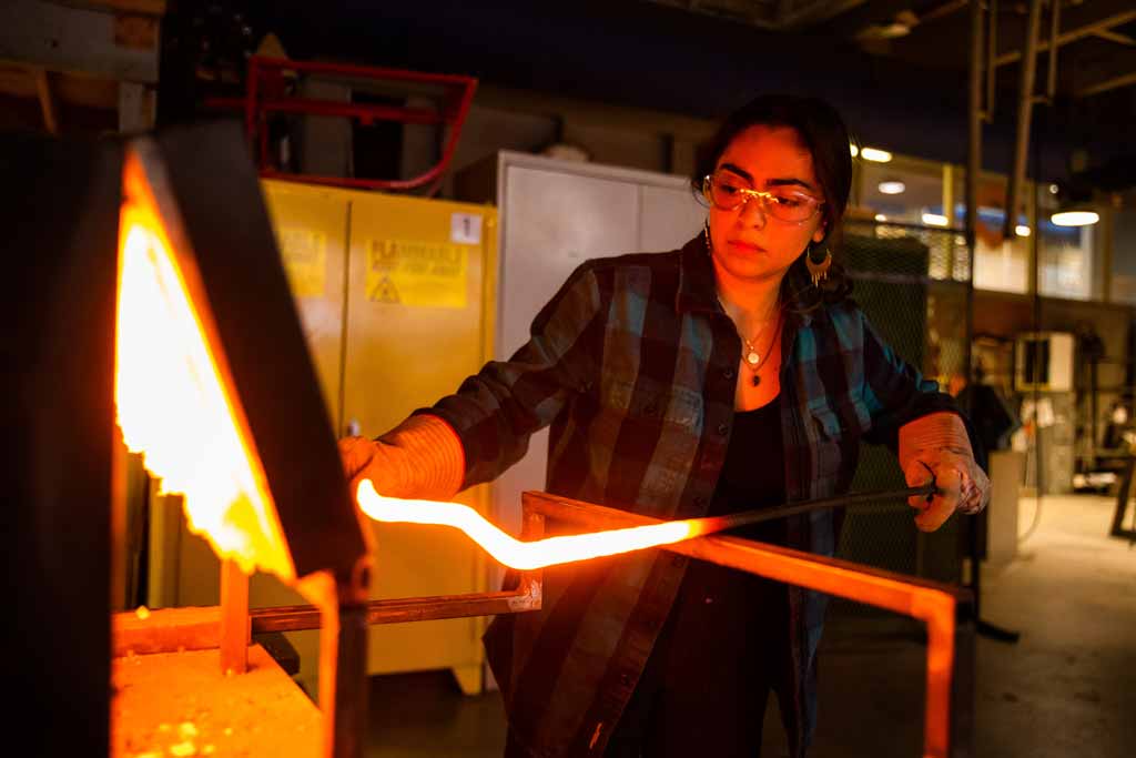 A woman working with sculpture in the metalworking facilities at UT.