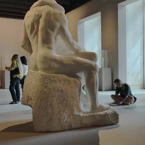 A picture of an art student in a gallery with a large marble sculpture