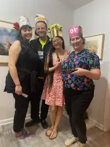 four people posing for a photo wearing paper crowns