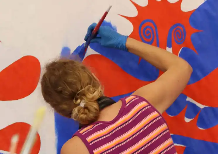 Woman painting in bright red and blue shapes
