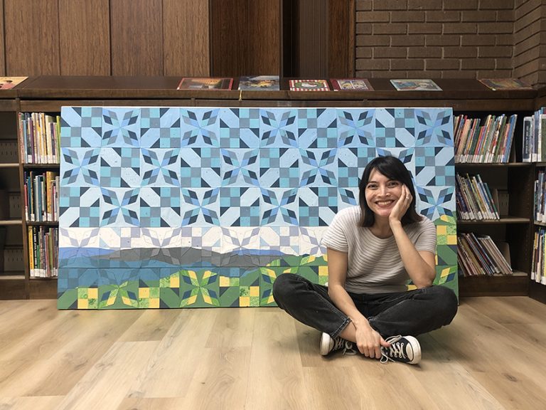Jade Hoyer sitting in front of blue and green artwork