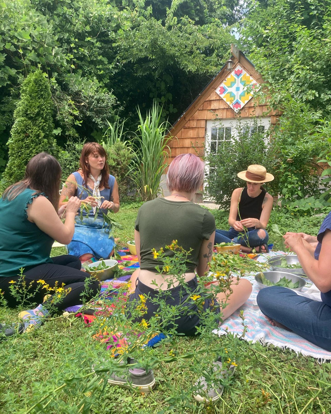 Ashlee Mays, with others, seated in the grass during a workshop at the Museum of Infinite Outcomes