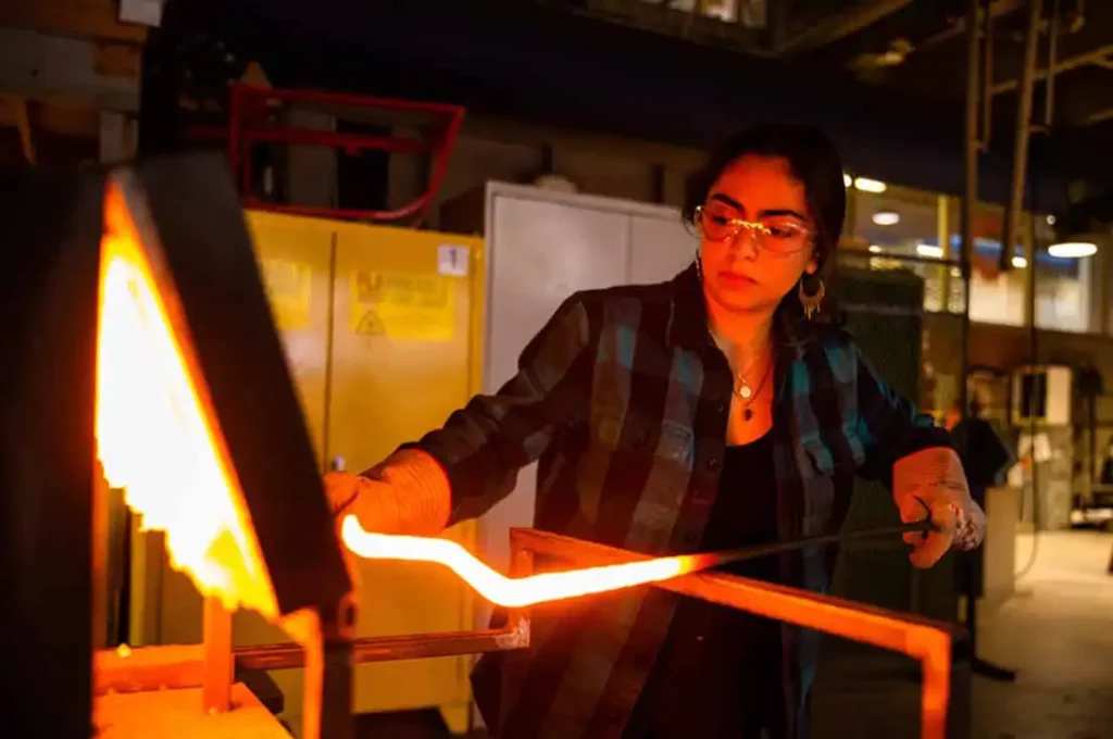 Female student sculpts at the forge