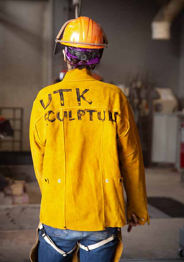 A student wearing a jacket with UTK Sculpture written on the back