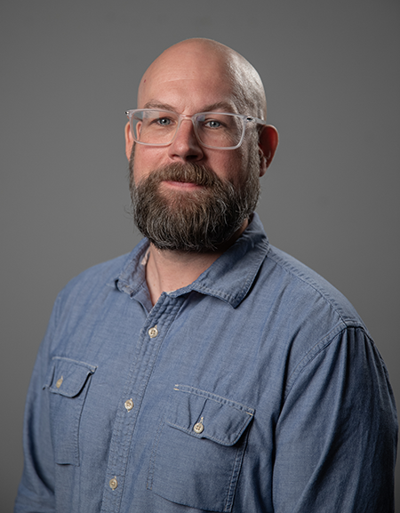 Headshot photo of Jered Sprecher against gray background