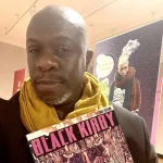 Stacey Robinson holding a booklet that says Black Kirby on the cover