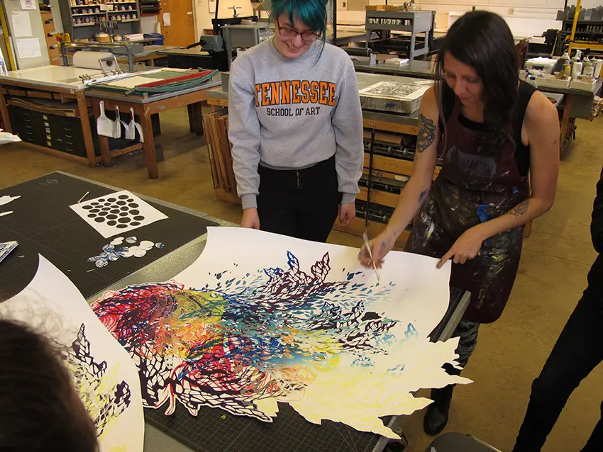 Crystal Wagner (MFA ’08) works with a printmaking student on her screenprinting project for the 2015 SGCI conference exhibition.