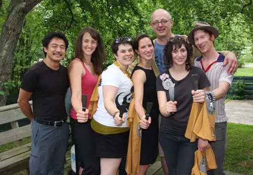 An outdoor group photo with people holding knives