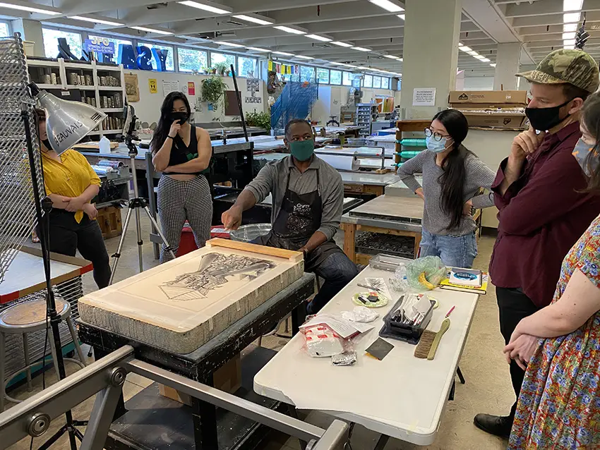 Steve A. Prince talks to graduate students about his drawing on a litho stone during his visit in September 2021.  Prince also worked with faculty and staff in the completion of “True Vine,” a 4 x 8 foot relief print during his visit.
