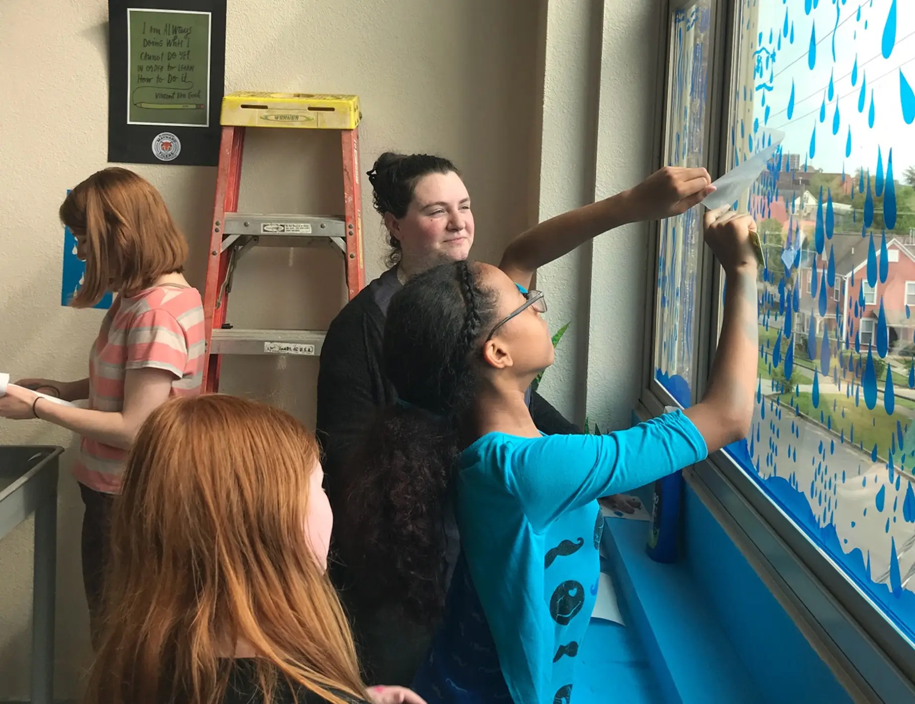 Students putting decals on a window by a teacher