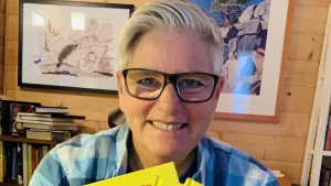 Photo of Paige Braddock holding books in an office