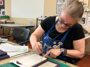Tatiana Potts, UT alumna, works on printmaking a book.