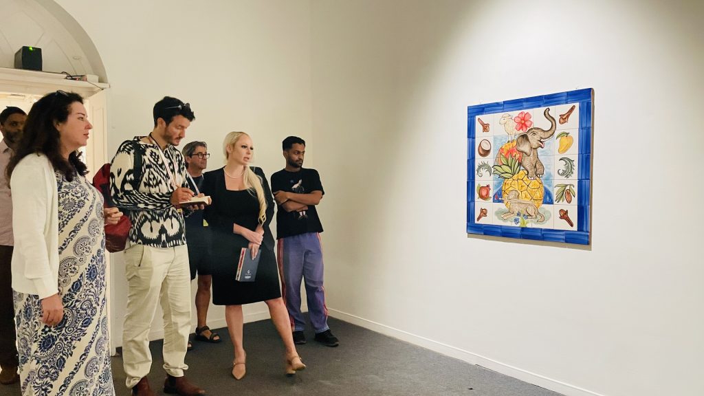 A group of people examine a painting of an elephant. 