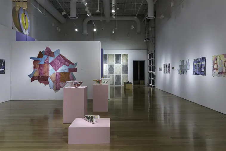 An entire gallery holds printed artwork on the walls and paper items on pedestals around the entire room. 