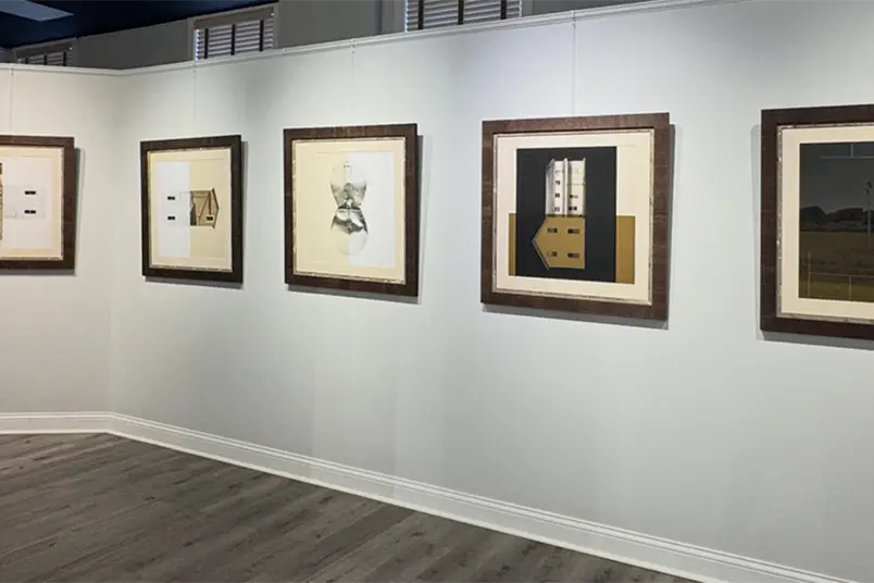 A collection of five pieces of artwork hang on a wall, titled "Specific to Site: Mapping Time and Place." 