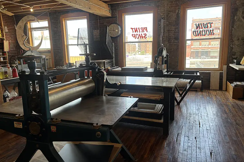 Two letterpresses and pressing equipment pictured inside the Twin Hound Print Shop. 