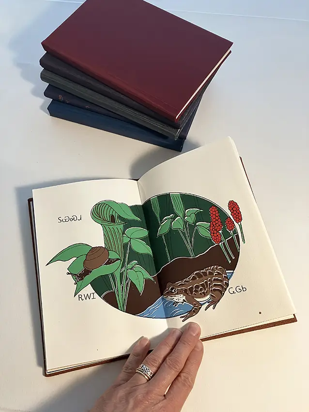 Tatianna Potts holds a booklet open with an artistic drawing of flowers depicted inside. 