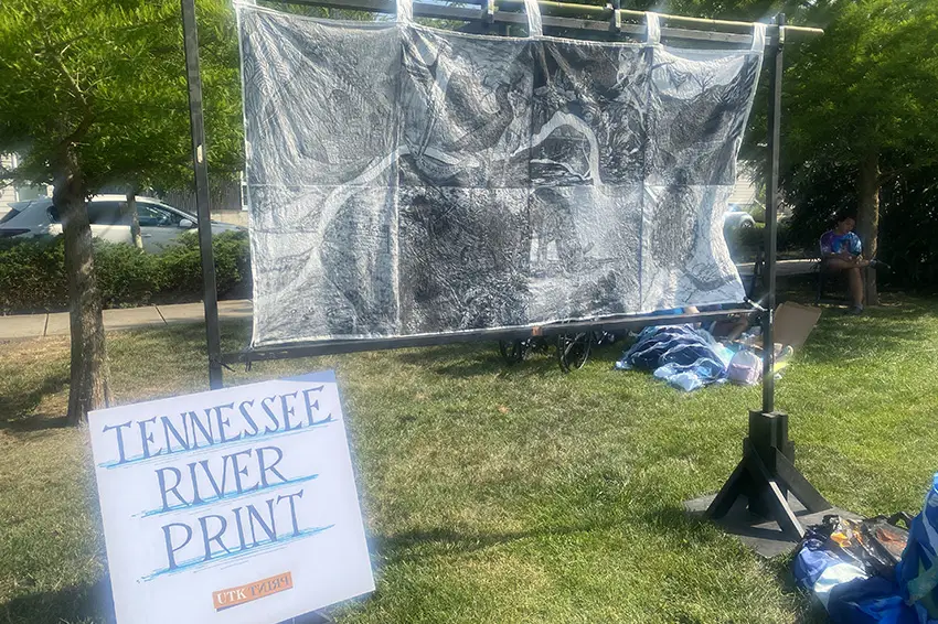 An art banner hangs outside with a sign that reads "Tennessee River Print."