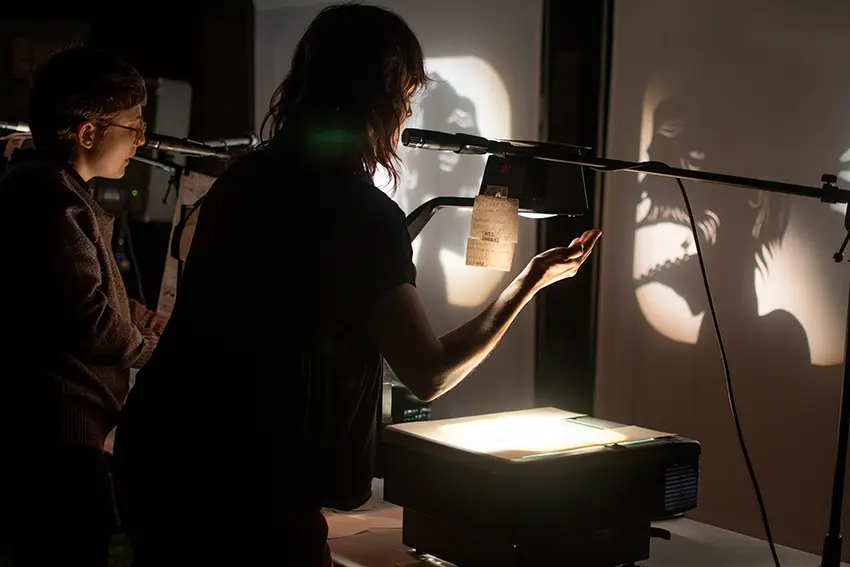 Artistic photo a women with her hands underneath a lamp in a dark room, making intentional shaped shadows on the walls. 
